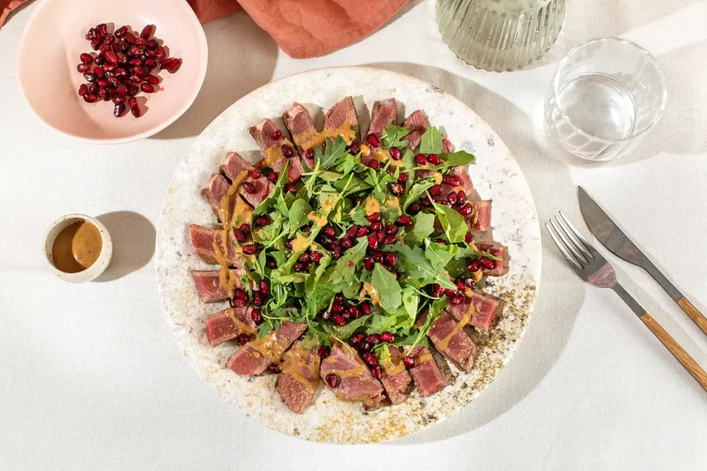 Ternera a la parrilla con rúcula y granada en plato saludable equilibrado