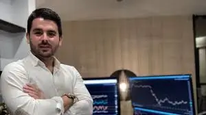 Enrique Moris, fundador de Tradeando Day Academy, posando con brazos cruzados delante de múltiples monitores con gráficos de bolsa.