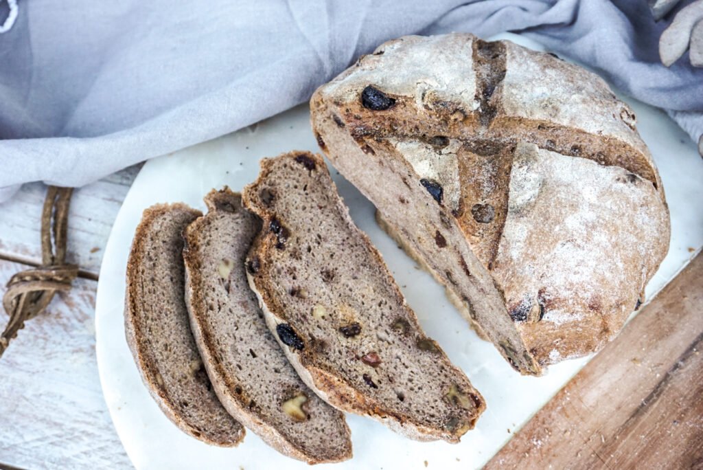 Hogaza de pan artesano sin gluten con corteza crujiente y miga esponjosa sobre tabla de madera.