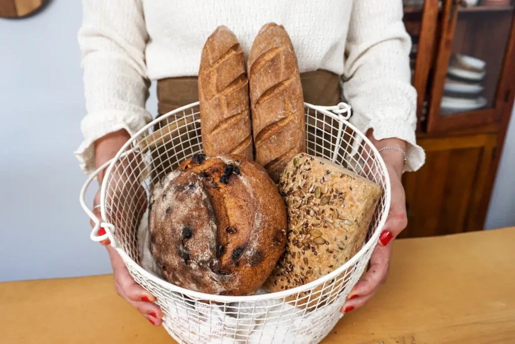 Cesta con variedad de panes sin gluten: baguettes crujientes, hogaza rústica y pan de semillas artesanal hecho en casa.